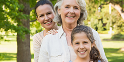 Mother, grandmother, and daughter smiling outdoors