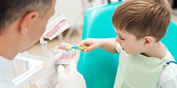 Dentist showing young boy how to brush teeth