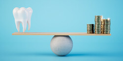 a model tooth and gold coins set on a balance beam