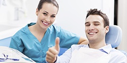 Assistant with patient in dental chair giving thumbs up