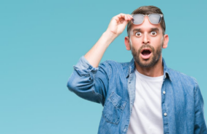 Man raising his glasses and eyebrows in surprise