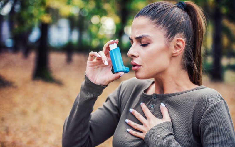 a woman outside using an inhaler for asthma